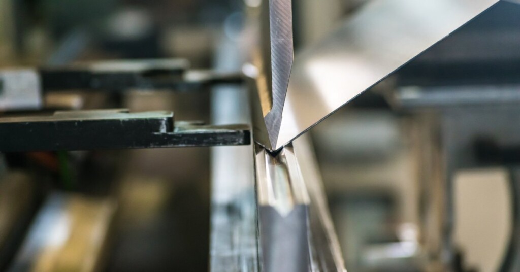 A magnified view of a piece of sheet metal being bent in a metal fabrication process using metal supports.